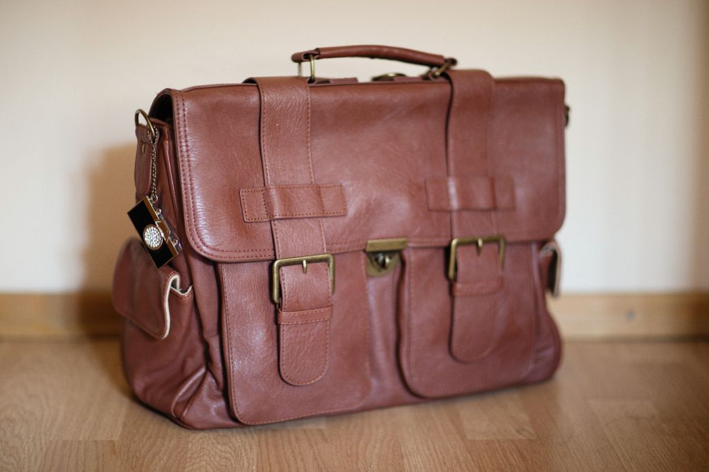 Photo by: Alexey Demidov - Stylish brown leather satchel on wooden flooring, perfect for travel or business 
